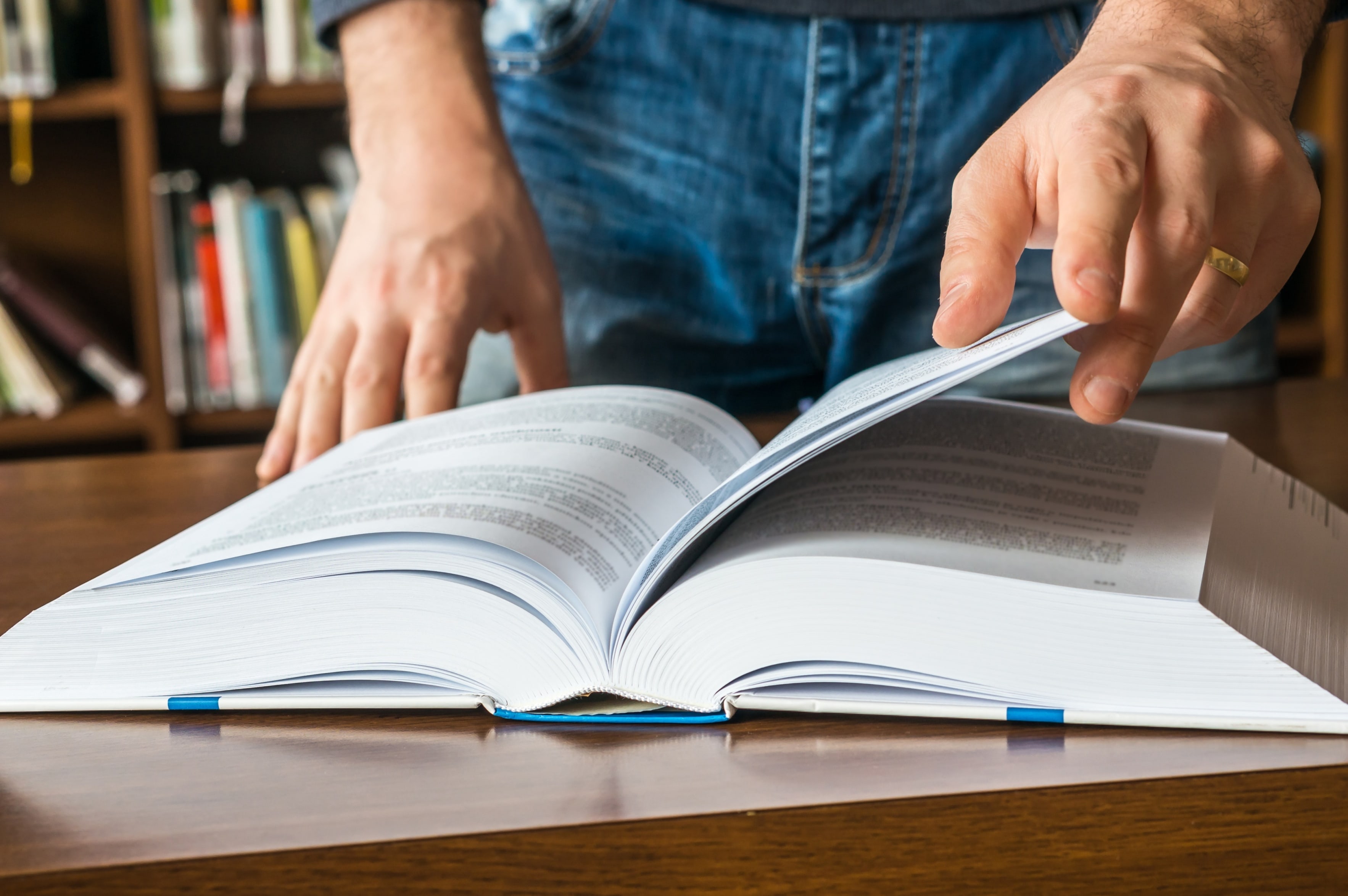 Plano aproximado das mãos de uma pessoa a folhear um livro