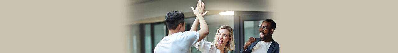 Duas pessoas a celebrar com um high five enquanto uma terceira pessoa observa